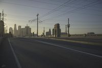 an empty highway with power lines leading to city buildings in the back ground and road tracks