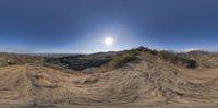 a panorama view of a person jumping a ramp over a dirt hill with an open area below