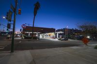 night time view of a stoplight, street signs and store front at an intersection