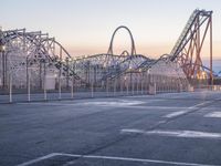 a large roller coaster is on the concrete surface by itself with an empty parking lot in front of it