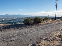 a bicycle on a dirt road surrounded by some telephone poles and wires above the hills