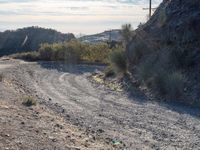 a dirt road in the desert with a mountain in the background that has power lines over it