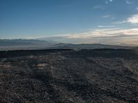 a person sitting on a mountain while looking at the horizon to see a fire burning