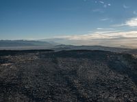 a person sitting on a mountain while looking at the horizon to see a fire burning