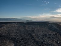 a person sitting on a mountain while looking at the horizon to see a fire burning