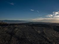 a person sitting on a mountain while looking at the horizon to see a fire burning