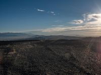 a person sitting on a mountain while looking at the horizon to see a fire burning