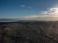 a person sitting on a mountain while looking at the horizon to see a fire burning