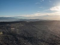 a person sitting on a mountain while looking at the horizon to see a fire burning