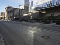 a deserted street is in front of the city building on a sunny day with the sun coming in