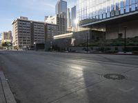 a deserted street is in front of the city building on a sunny day with the sun coming in