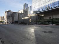 a deserted street is in front of the city building on a sunny day with the sun coming in