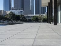 a paved concrete sidewalk surrounded by tall buildings and a pond at the end of it