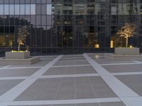 two concrete planters sit in front of a building at dusk with an exterior reflection