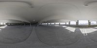 a fish - eye lens shows people walking along an empty area with a domed ceiling