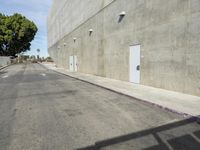 there is an empty building and an exit gate to the street next to it that leads down a wide city sidewalk
