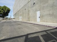 there is an empty building and an exit gate to the street next to it that leads down a wide city sidewalk