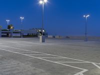 an empty parking lot with a few street lights in front of it and a car parking lot and sidewalk next to the road