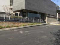 the empty parking lot at the side of the road near a building that is built into a concrete block