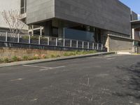 the empty parking lot at the side of the road near a building that is built into a concrete block