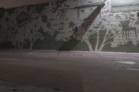 an empty parking lot with a wall painted with trees and benches in the background, a tree with many leaves, blue lines painted on it