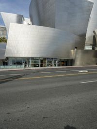 an empty street in front of a large white building with glass walls on the sides