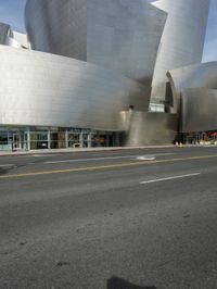 an empty street in front of a large white building with glass walls on the sides