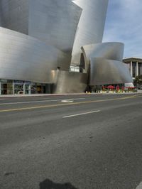 an empty street in front of a large white building with glass walls on the sides