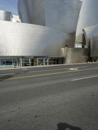 an empty street in front of a large white building with glass walls on the sides