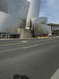 an empty street in front of a large white building with glass walls on the sides