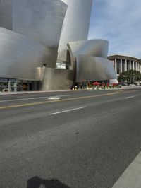 an empty street in front of a large white building with glass walls on the sides