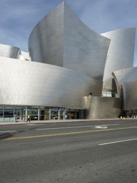 an empty street in front of a large white building with glass walls on the sides