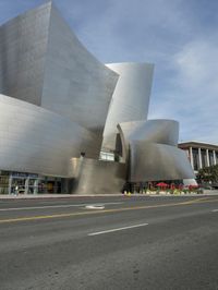 an empty street in front of a large white building with glass walls on the sides