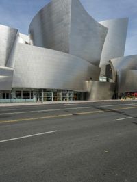 an empty street in front of a large white building with glass walls on the sides