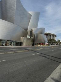 an empty street in front of a large white building with glass walls on the sides