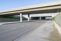 a freeway under an elevated bridge leading to a covered area for cars and people on the road