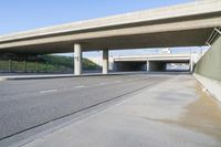 a freeway under an elevated bridge leading to a covered area for cars and people on the road