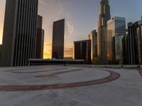 a view of the city skyline with buildings in the background and a circular symbol drawn on the ground at sunset