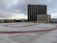 the letter u is painted in red on the asphalt outside of a city building with other buildings behind it