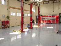 two red lifts are used to work in a garage area while a worker is at work