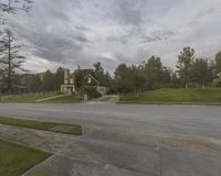 a home in the street is shown with a driveway in front of it with grass and tall trees