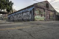 an old building with a wall with graffiti all over it's side on a street