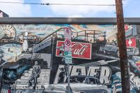 a graffiti painting on the side of a wall depicting a car at an outdoor cafe