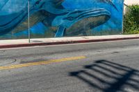 the blue whale mural on the side of the building is part of a street corner