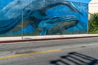 the blue whale mural on the side of the building is part of a street corner