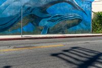 the blue whale mural on the side of the building is part of a street corner