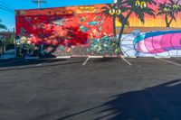 an empty parking lot is painted with colorful graffiti art and palm trees on the sides