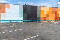 the back wall is lined with colorful, geometric pieces of art and stands in a parking lot