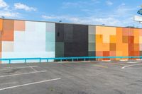 the back wall is lined with colorful, geometric pieces of art and stands in a parking lot