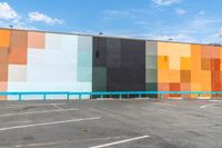 the back wall is lined with colorful, geometric pieces of art and stands in a parking lot